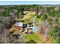 Expansive aerial view of a red home, surrounded by lush greenery, mature trees and a long private drive at 3227 Morrow Farm Ln, Chapel Hill, NC 27516