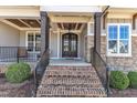 Inviting front porch showcasing a brick staircase, dark stained columns, and an elegant, double-door entrance at 3240 Donlin Dr, Wake Forest, NC 27587