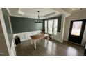 Bright dining room with modern chandelier, accent wall, wainscoting, and ample natural light at 49 W Copenhaver Dr, Clayton, NC 27527