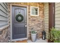 A stylish front door with stone siding, decorative wreath, and potted flowers at 517 Aronia Dr, Hillsborough, NC 27278