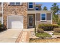 Close-up of the townhome's entrance, featuring a stone facade, attached garage, and decorative landscaping at 5433 Jessip St, Morrisville, NC 27560