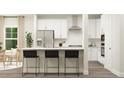 Modern kitchen featuring white cabinets, stainless steel appliances, and stylish black bar stools at 712 Swim Cave Ln, Wendell, NC 27591