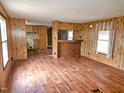 View of the open living room with laminate floors and wood paneled walls at 8025 Hebron Church Rd, Garner, NC 27529