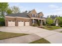 Charming brick home featuring a three-car garage, with a large driveway and covered front porch at 832 Mountain Vista Ln, Cary, NC 27519