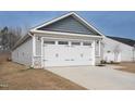 Attached two car garage with white door and stone veneer base on a home with gray siding at 8630 Kenridge Ln, Fuquay Varina, NC 27526