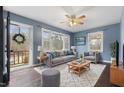 Bright living room with large windows, hardwood floors, stylish furniture, and a ceiling fan at 902 Long Ave, Garner, NC 27529