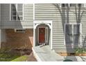 Inviting red front door features a decorative wreath, complemented by neutral siding and manicured landscaping at 100 Hunting Chase # 1-B, Cary, NC 27513