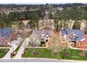 An aerial view shows the traditional home with a long driveway and manicured landscaping near a golf course at 10841 Round Brook Cir, Raleigh, NC 27617