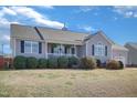 View of a single-story house featuring gray siding, black shutters, well-maintained landscaping, and an attached two-car garage at 131 Woodglen Dr, Clayton, NC 27527