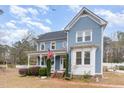 Charming two-story home with blue siding, a welcoming porch, and manicured landscaping at 2601 Forestville Rd, Wake Forest, NC 27587