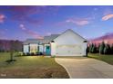 Beautiful single-story home with a two-car garage and blue door under a vibrant sunset sky at 28 Sandcastle Ln, Four Oaks, NC 27524
