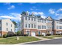 Townhomes with brick facade and private driveways on a well-manicured lawn under a sunny sky at 301 Coral Creek Ln, Morrisville, NC 27560