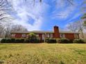 Charming red brick home featuring mature landscaping, a brick chimney, and a well-manicured front yard at 3015 Nc Hwy 87 South, Graham, NC 27253