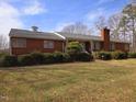 Charming red brick home featuring mature landscaping, a brick chimney, and a well-manicured front yard at 3015 Nc Hwy 87 South, Graham, NC 27253