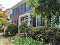 A front exterior view of a two-story brick home with a periwinkle front door, mature shrubs and landscaped lawn at 307 Kellyridge Dr, Apex, NC 27502