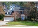 Two-story brick home with black shutters, blue door, attached garage, and a green lawn at 307 Kellyridge Dr, Apex, NC 27502