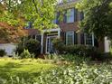 A close exterior view featuring a charming two-story brick home, manicured lawn, and delightful periwinkle front door at 307 Kellyridge Dr, Apex, NC 27502