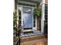 Charming brick home entrance featuring a welcoming periwinkle door with sidelights and a striped welcome mat at 307 Kellyridge Dr, Apex, NC 27502