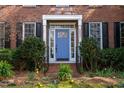 A close-up of the brick home's front entrance, showcasing a blue door with glass sidelights and blooming landscaping at 307 Kellyridge Dr, Apex, NC 27502