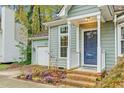 Charming front exterior featuring a blue front door, manicured flower bed, and attached garage at 4117 Olde Coach Rd, Durham, NC 27707