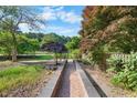 Landscaped path through lush yard with garden accents and colorful trees at 4811 New Sharon Church Rd, Hillsborough, NC 27278