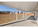 View of covered back patio with concrete flooring that overlooks an expansive backyard and neighborhood homes at 65 Hickory Run Ln, Franklinton, NC 27525