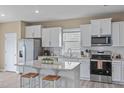Well-lit kitchen featuring stainless steel appliances, granite countertops, white cabinetry, and a kitchen island with seating at 656 Dallas Rose Dr, Wendell, NC 27591
