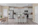 Open kitchen featuring stainless steel appliances, granite countertops, a kitchen island with seating, and white cabinetry at 656 Dallas Rose Dr, Wendell, NC 27591
