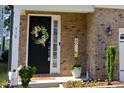 Close-up of front door with beautiful wreath, brick facade, and manicured landscaping at 938 Haybeck Ln, Apex, NC 27523