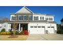 Attractive exterior showcasing stone accents, a three-car garage, and vibrant landscaping under a clear blue sky at 1532 Champlain Crest Way, Cary, NC 27513