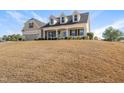 Inviting two-story home featuring dormer windows, covered porch, attached garage, and lawn on a sunny day at 21 Tracker Ct, Garner, NC 27529