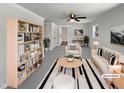 Bright, virtually staged living room with contemporary furniture, a ceiling fan, and a large bookshelf at 317 Gary St, Raleigh, NC 27606