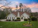 A beautiful home with a well-kept lawn, lush bushes, and mature trees under a lovely sunset sky at 5300 Mandrake Ct, Raleigh, NC 27613