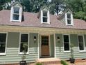 Inviting home exterior featuring light green siding, dormer windows, and a wood front door at 1116 Shadywood Ln, Raleigh, NC 27603