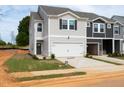 Two-story townhome showcasing its gray siding and 2-car garage, with minimal landscaping and signage in place at 1165 Abbott St, Mebane, NC 27302