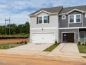 Two-story townhome with a 2-car garage, light gray siding, and a well-lit driveway at 1165 Abbott St, Mebane, NC 27302