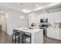 Bright kitchen boasts white cabinets, stainless appliances, an island with bar seating, and stylish backsplash at 1206 Linkwood Way, Fuquay Varina, NC 27526