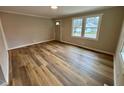 Bright living room features new wood flooring and a large window that fills the space with natural light at 1405 Parham St, Henderson, NC 27536