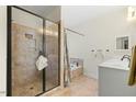 A spacious bathroom with a glass shower enclosure, soaking tub, and white vanity at 203 Streamside Dr, Sanford, NC 27330