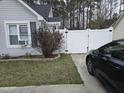 View of the side yard with neat landscaping, a white fence, and a glimpse of a parked car at 225 Sebastian Way, Rocky Mount, NC 27804
