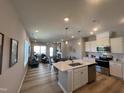 Open-concept kitchen features an island with seating, stainless steel appliances, and sleek countertops at 228 Pecan Valley Way, Four Oaks, NC 27524