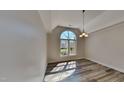 Elegant dining room with a large arched window, modern light fixture, and gray floors creating an airy space at 3704 Sky Meadow Dr, Apex, NC 27539