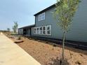 A green-sided home features newly laid mulch beds and sapling trees along its exterior sidewalk at 50 Rainfall Dr, Pittsboro, NC 27312