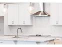 Bright kitchen features white cabinets, a large island, modern fixtures, and stainless steel vent hood at 63 Tee Time Ter, Benson, NC 27504