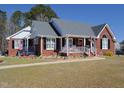 A well-maintained red brick home with a welcoming front porch, lush lawn, and tasteful landscaping at 703 E Stanley St, Four Oaks, NC 27524