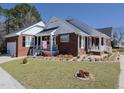 Inviting brick home featuring a two-car garage, well-kept lawn, and charming front porch area at 703 E Stanley St, Four Oaks, NC 27524