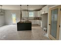 Bright kitchen featuring white cabinets, a stylish pantry door, and a dark green kitchen island at 9600 Stallings Rd, Spring Hope, NC 27882