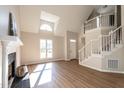 Bright living room with a vaulted ceiling, fireplace, staircase, and wood-look flooring at 100 Wiley Oaks Dr, Wendell, NC 27591