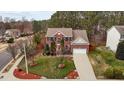 Aerial view of a brick home with well-kept lawn and landscaping, long driveway, and 2-car garage at 1046 Upchurch Farm Ln, Cary, NC 27519