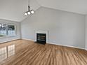 Open living room with a fireplace, vaulted ceiling, and new light brown floors at 108 New Castle Ct, Youngsville, NC 27596